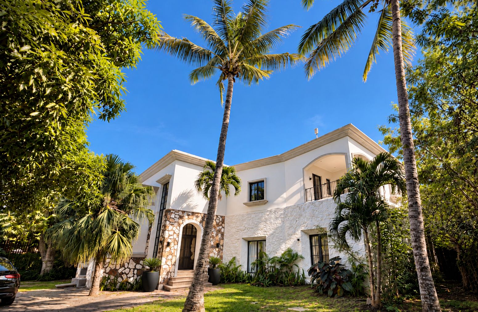 Villa exterior – stone arch entry, curved balcony & tall palms frame the villa