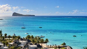 A coastal resort with clear turquoise waters, boats, and palm trees.