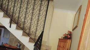 Un escalier agrémenté d’une rampe décorative, un meuble en bois orné de fleurs et un vase placé sur le palier.