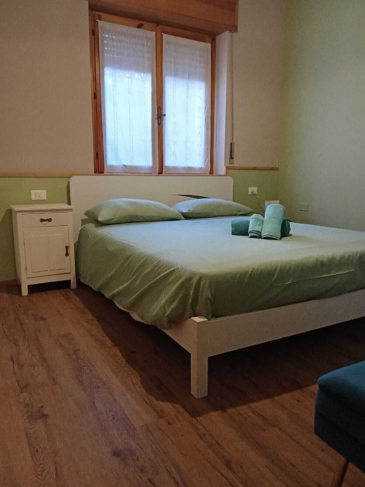 A bedroom with a bed, nightstand, and window.