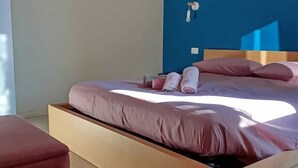 A modern bedroom with a wooden bed, a red bench, and a blue accent wall. - Real Italy Retreat: Village, Views & Silence (Cimbergo)