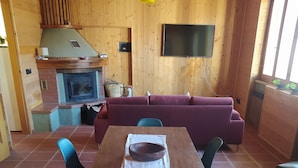 A wooden interior with a dining table, chairs, a sofa, a TV, and a fireplace. - Real Italy Retreat: Village, Views & Silence (Cimbergo)