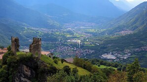 A mountainous landscape with a historic castle ruin and a valley with a town. - Real Italy Retreat: Village, Views & Silence (Cimbergo)