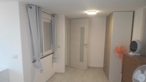 A hallway with a door, a window with curtains, a fan, and a mirror on a dresser. - Apartment '2 Vista Mare' with Sea View, Wi-Fi and Air Conditioning (Ischia)