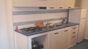 A kitchen with white cabinets, a blue countertop, a gas stove, a sink, and a refrigerator. - Apartment '2 Vista Mare' with Sea View, Wi-Fi and Air Conditioning (Ischia)