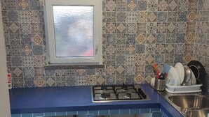 A kitchen with patterned tiles, a gas stove, a sink, and a window.