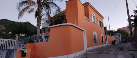 Un edificio residencial con un muro curvo, un acceso con reja y vista a la calle.