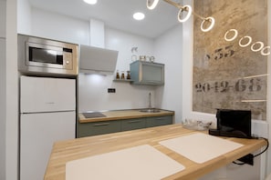 Una cocina moderna con microondas integrado, un lavabo y una encimera de madera.