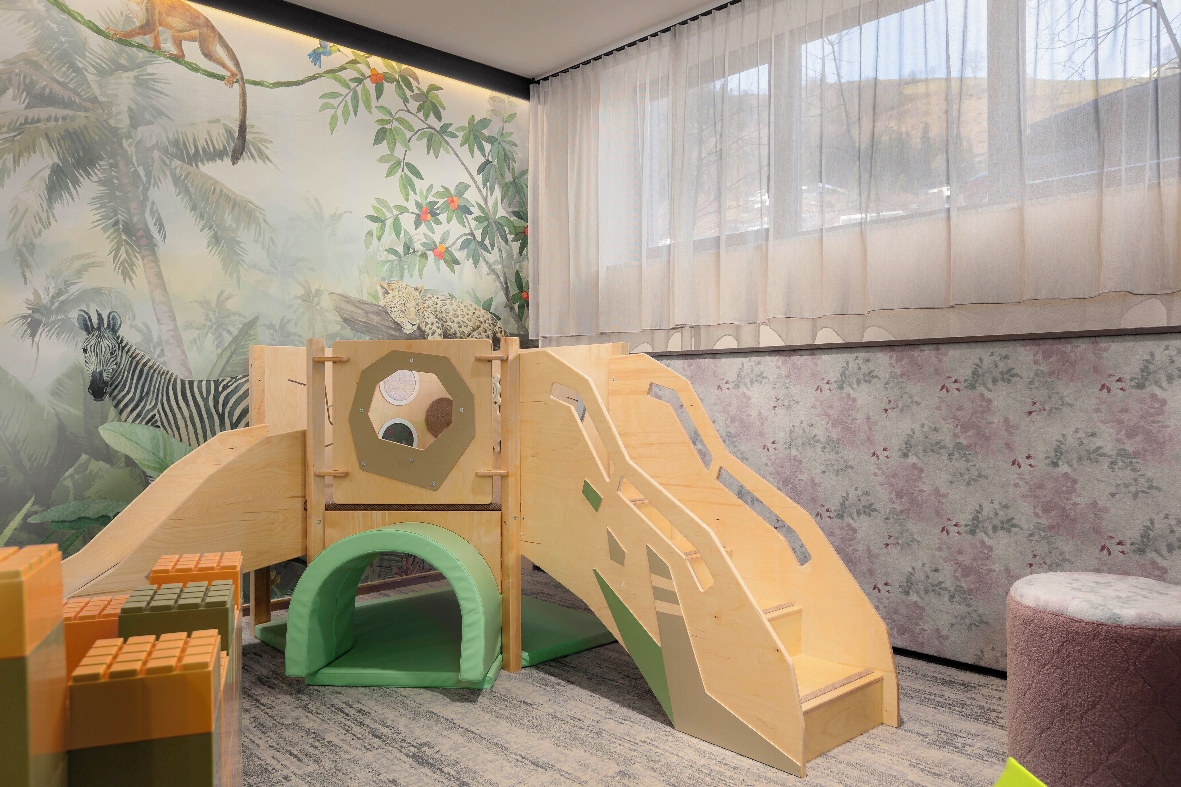 A children's play area with a slide, climbing structure, and a green tunnel.