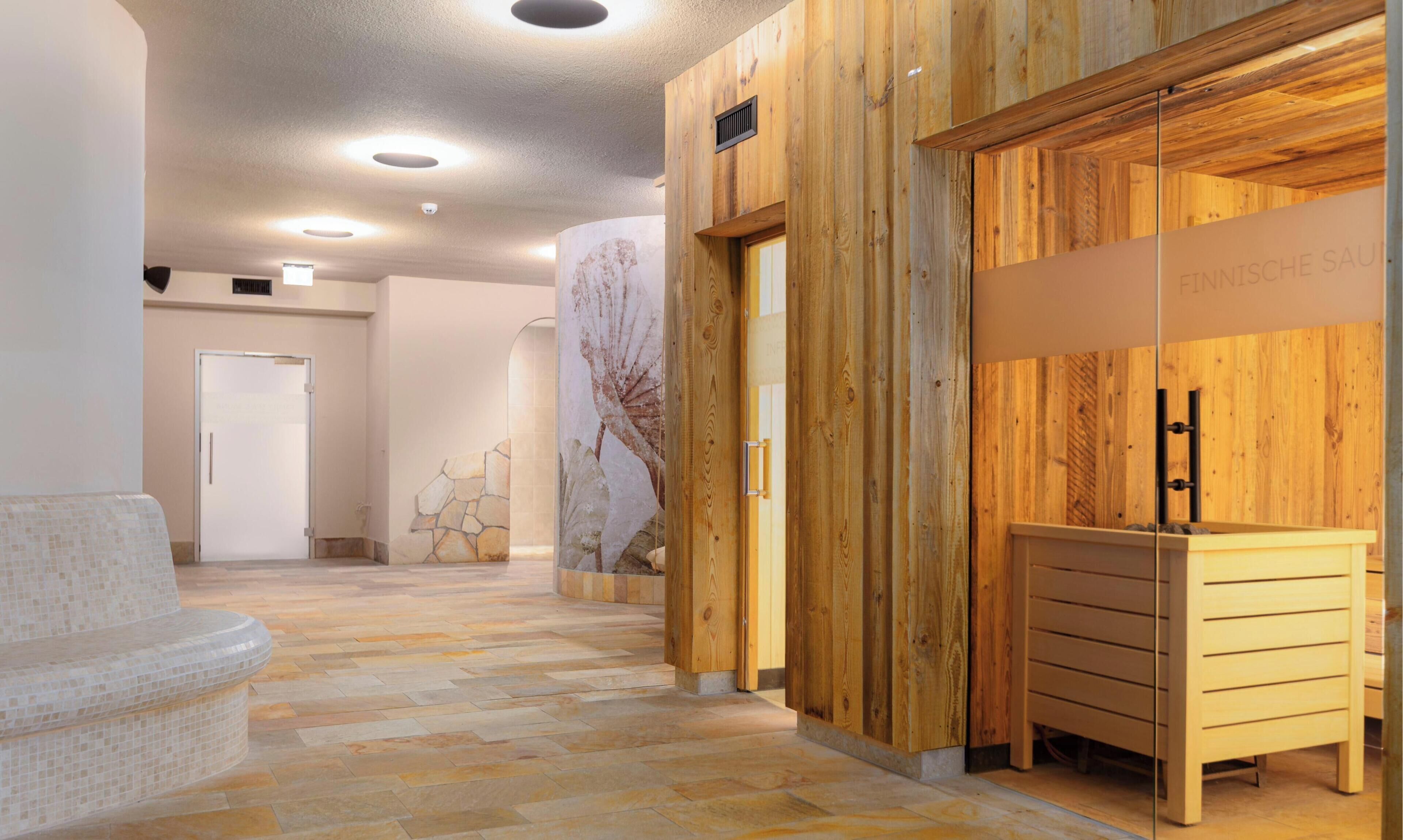 Un pasillo con pared de madera, pared de piedra con un mural de un árbol y un mostrador de recepción con detalles de madera.
