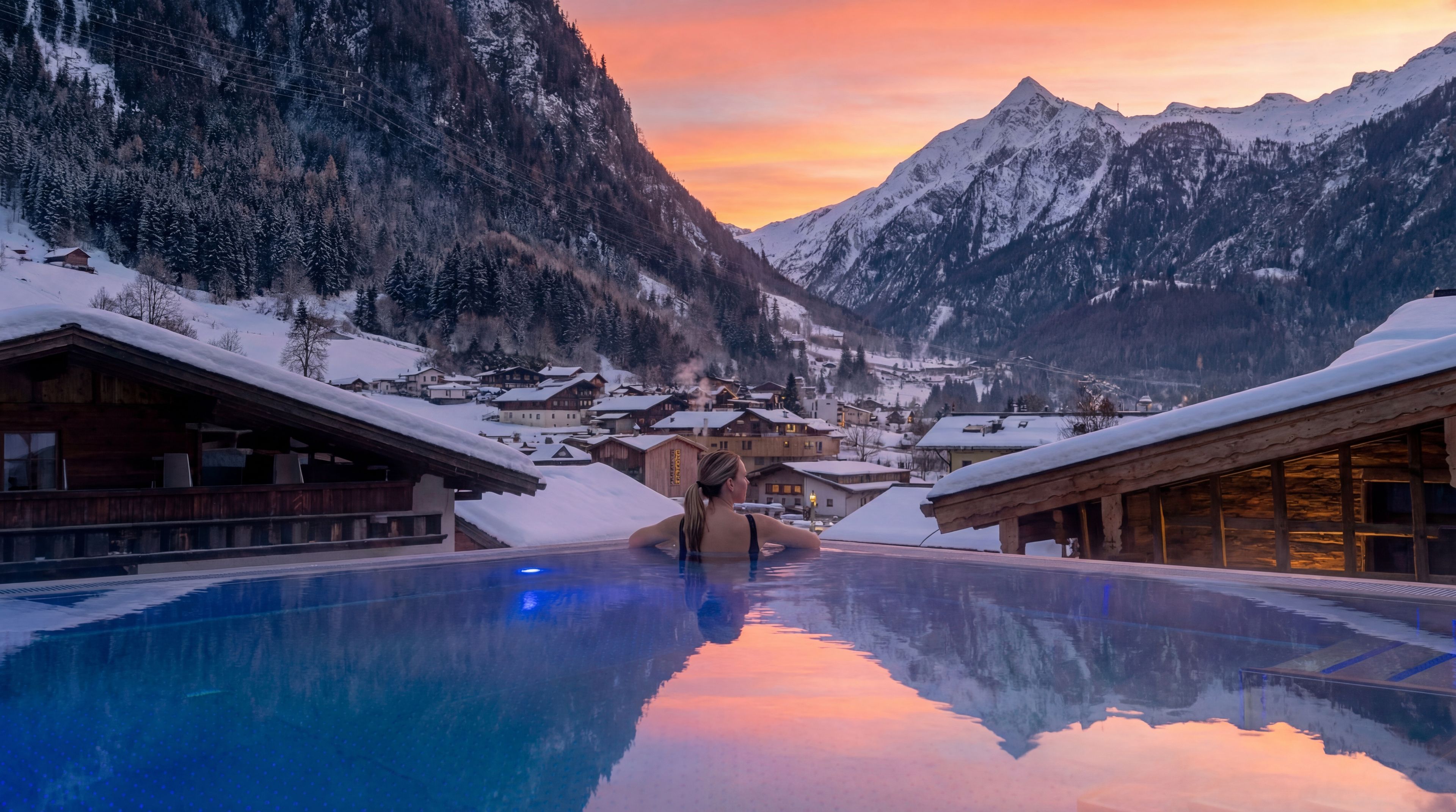 Ein Pool mit Blick auf schneebedeckte Berge und ein Dorf.