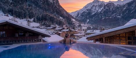 A pool with a view of snow-covered mountains and a village.