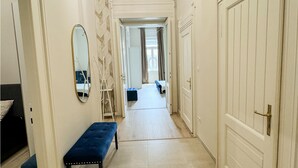 A hallway with a bench, a mirror, and a door leading to another room.