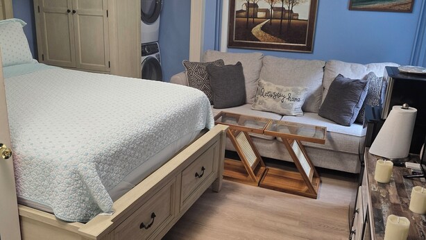 Un dormitorio con cama, cómoda, sofá y un cuadro en la pared.