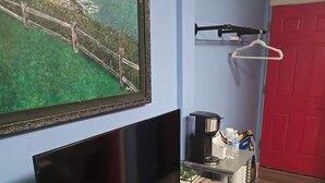 Una sala de estar moderna con televisor de pantalla plana, mueble de madera, velas, controles remotos y un cuadro en la pared.