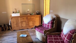 A cozy living room with a wooden cabinet, two upholstered chairs with patterned cushions, a small wooden table, and a mirror on the wall. - Chambre et table d'hôtes LE VERGER near Sancerre, Guédelon, Loire by bike, A77 motorway (Léré)