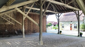A covered outdoor area with a gravel floor, wooden benches, and a rustic wooden wall. - Chambre et table d'hôtes LE VERGER near Sancerre, Guédelon, Loire by bike, A77 motorway (Léré)