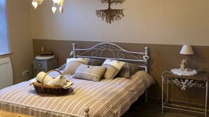 A neatly made bed with striped bedding, a bedside table with a lamp, a wall-mounted tree decoration, and a hanging light fixture. - Chambre et table d'hôtes LE VERGER near Sancerre, Guédelon, Loire by bike, A77 motorway (Léré)
