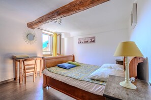 Ein Schlafzimmer mit einem hölzernen Bett, einem Schreibtisch, einem Stuhl, einer Lampe und einem Wandspiegel.