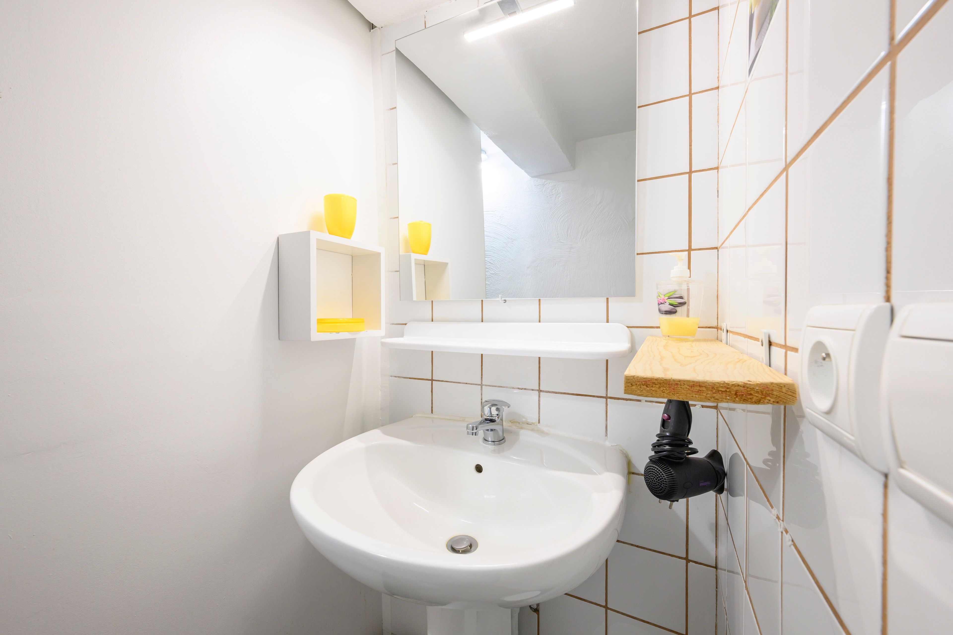 Un bagno con un lavandino bianco, uno specchio e un portasciugamani.
