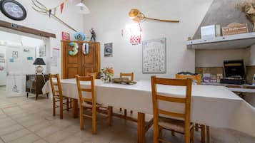 Un coin repas avec une table dressée pour quatre personnes, des chaises en bois, une horloge au mur et une décoration rustique.