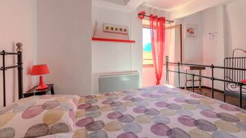 Een slaapkamer met een bed, een rode lamp, een radiator en een raam met een rood gordijn.