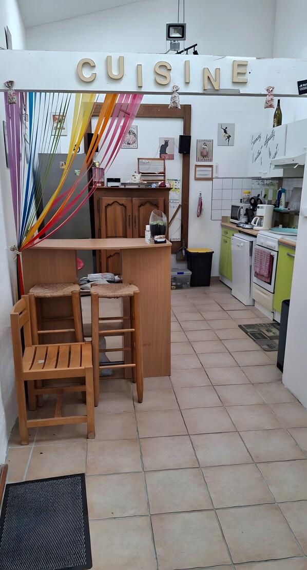 A kitchen with a wooden table and chairs, a countertop, and a sign that reads 'CUISINE'. - 'Coquelicot' Room with Mountain View, Shared Terrace, and Wi-Fi (Montbrun-les-Bains)