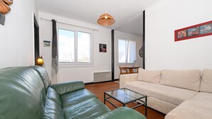 A living room with a green leather sofa, a beige sofa, and a glass coffee table. - Spacious T2 with Unobstructed View (Lorient)