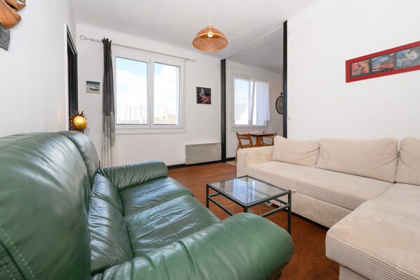 A living room with a green leather sofa, a beige sofa, and a glass coffee table. - Spacious T2 with Unobstructed View (Lorient)