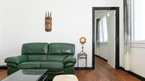 A green leather sofa, a small table, a decorative lamp, and a wall-mounted mask. - Spacious T2 with Unobstructed View (Lorient)