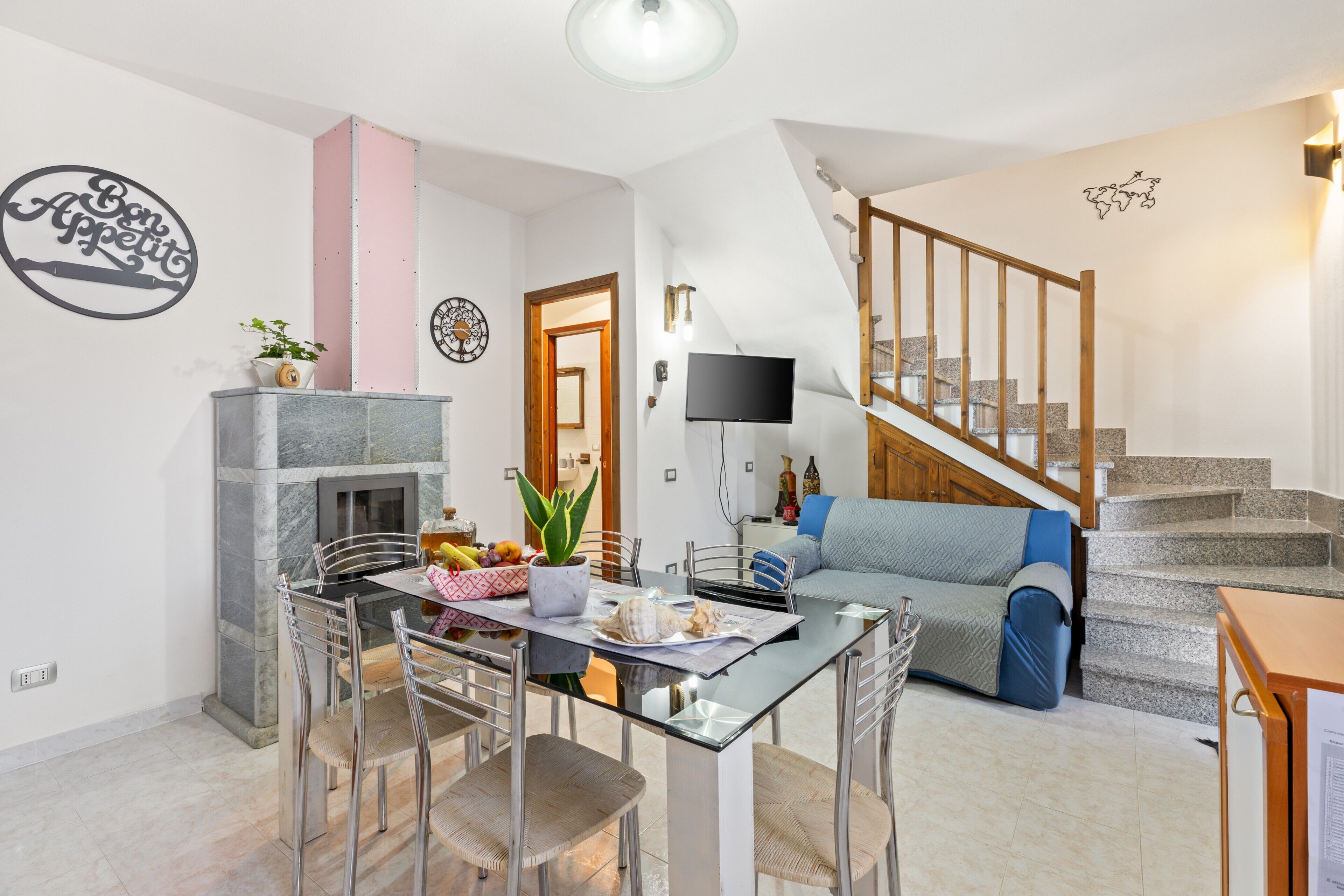 Un salon moderne avec une table à manger en verre, un canapé, une cheminée et un escalier.