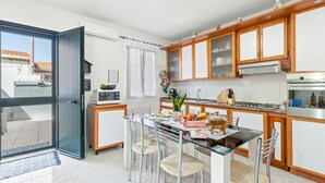 Una cocina moderna con armarios de madera, una mesa de comedor con sillas y vistas a través de una puerta abierta.