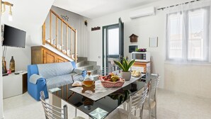 Una cocina moderna con una mesa de comedor, sillas, un televisor y una escalera que lleva a un nivel superior.