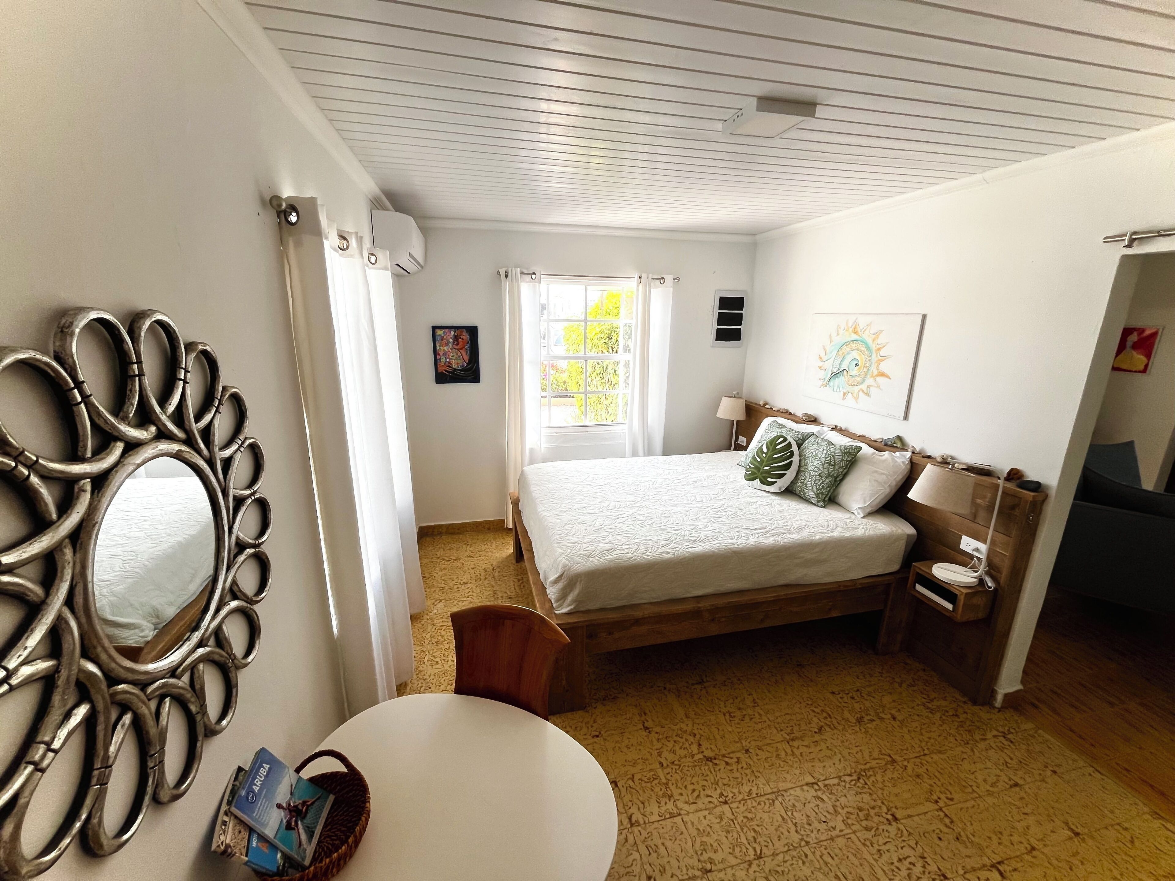 Une chambre à coucher avec un lit, une table de chevet, une lampe, un miroir et une fenêtre.