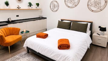 A modern bedroom with a bed, nightstand, chair, and decorative wall art.