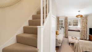 Un escalier menant à une chambre à coucher équipée d’un lit, d’une fenêtre et d’un téléviseur.