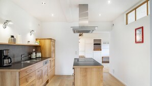 A modern kitchen with wooden cabinets, a central island, and built-in appliances. - Apartment '180 Grad' with Mountain View, Private Terrace and Wi-Fi (Mittenwald)