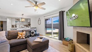 Ein modernes Wohnzimmer mit einer Couch, einem Hocker und einem flachbildfernseher an der Wand.