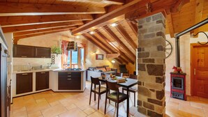 A rustic kitchen with wooden beams, a stone wall, and a fireplace. - Apartment 'Anita - Issime Valle D'aosta' with Balcony (Issime)