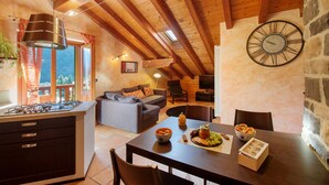 A cozy interior with a kitchen, dining area, and living space, featuring wooden beams, a stone wall, and a large clock. - Apartment 'Anita - Issime Valle D'aosta' with Balcony (Issime)