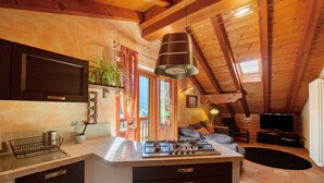 A kitchen with a gas stove, a sink, and a window overlooking a deck. - Apartment 'Anita - Issime Valle D'aosta' with Balcony (Issime)