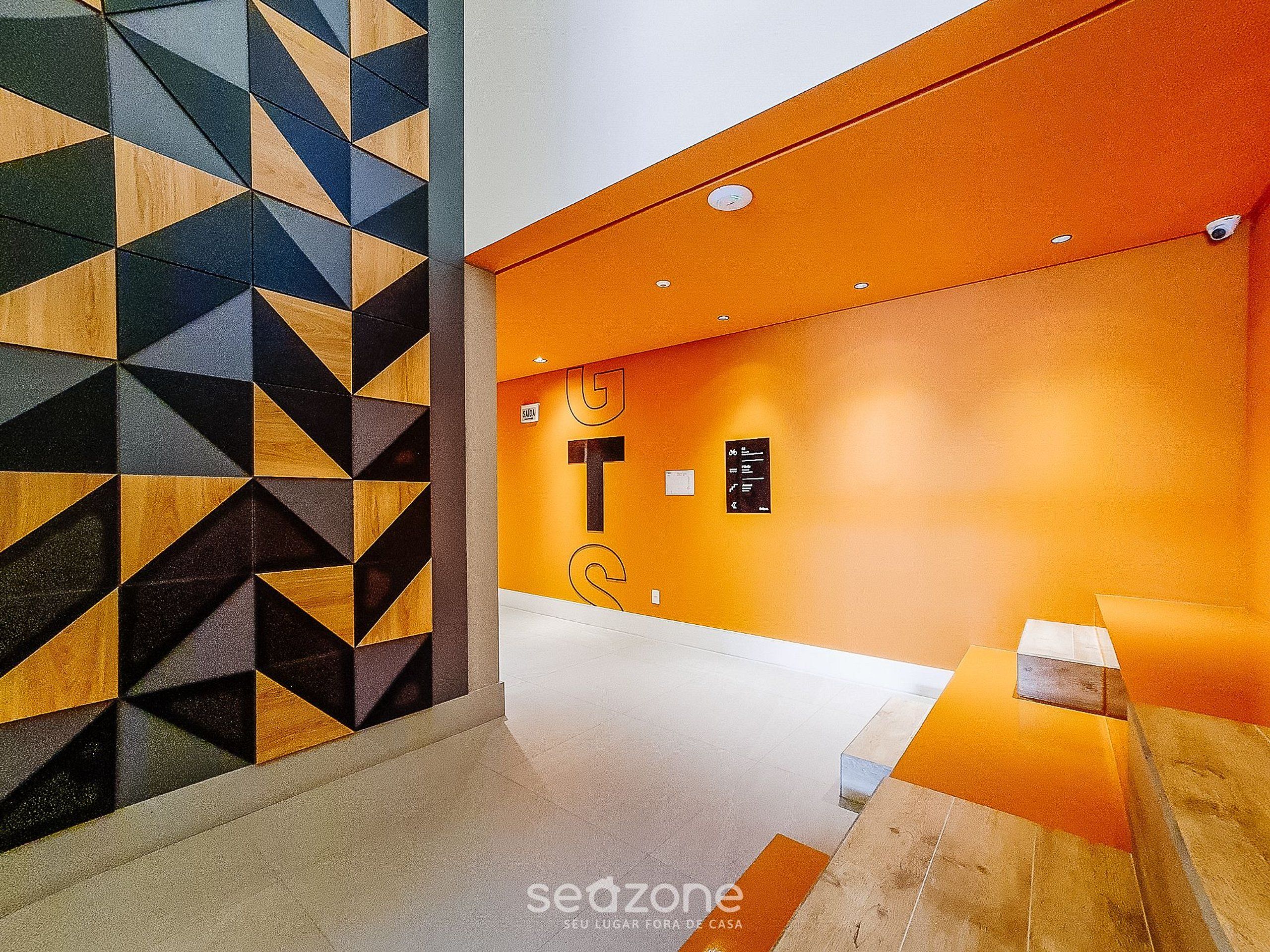 Un interior moderno con paredes de diseño geométrico, una pared de acento naranja brillante y un estilo minimalista y limpio.