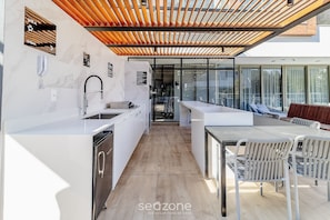 A modern kitchen with a built-in dishwasher, a sink, and a wooden ceiling. - Stay in a Building With a Pool, Gym, and Leisure - SSL (Florianópolis)