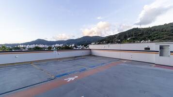 Un estacionamiento en la azotea con vistas a un paisaje urbano y montañas al fondo.
