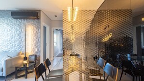 A modern dining area with a glass table, black chairs, and a hexagonal patterned wall. - Stay in a Building With a Pool, Gym, and Leisure - SSL (Florianópolis)
