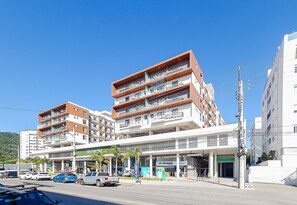 A multi-story hotel with balconies, a covered entrance, and a parking area. - Stay in a Building With a Pool, Gym, and Leisure - SSL (Florianópolis)