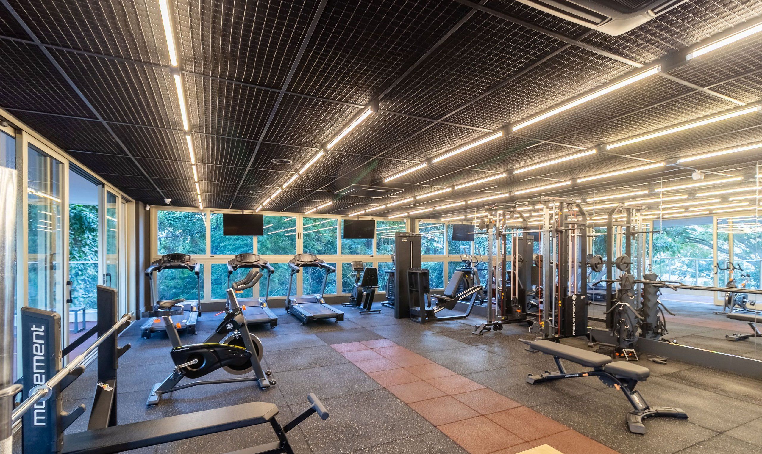 Un gimnasio moderno con cintas de correr, máquinas de pesas y colchonetas de ejercicio.