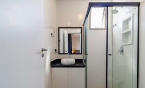 A modern bathroom with a glass shower enclosure, a sink with a mirror, and a toilet. - Stay in a Building With a Pool, Gym, and Leisure - SSL (Florianópolis)