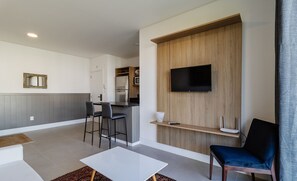 Een moderne woonkamer met een flatscreen televisie, een bijzettafeltje en twee barkrukken.
