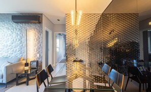 A modern dining area with a glass table, black chairs, and a hexagonal patterned wall. - Stay in a Building With a Pool, Gym, and Leisure - SSL (Florianópolis)